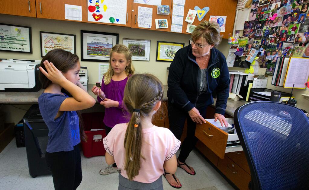 El Verano Elementary School office manager Barbara McInnis, helps her granddaughter Carlee Hinman, center, find a hair tie for her first grade friends Claudia Gonzalez, left, and Karina Kohnhorst during lunch.