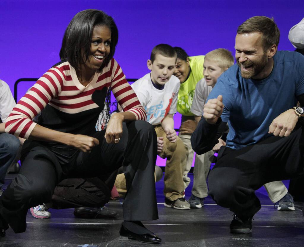 FILE - In this Feb. 9, 2012, file photo, first lady Michelle Obama and Bob Harper of 'The Biggest Loser,' right in blue shirt, do the Interlude dance during a Let's Move event with children from Iowa schools at the Wells Fargo Arena in Des Moines, Iowa. Harper tells TMZ he suffered a heart attack and was hospitalized for several days in February 2017. (AP Photo/Carolyn Kaster, File)