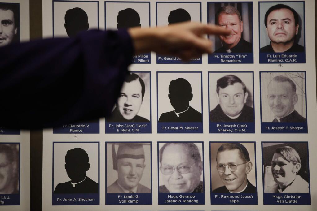 An advocate and survivor of sexual abuse, points to the photos of Catholic priests accused of sexual misconduct by victims during a news conference Thursday, Dec. 6, 2018, in Orange, Calif. Lawyer Mike Reck on Thursday said that's many more than those reported by the Diocese and demanded greater transparency. The Diocese of Orange says the lawyers are trying to re-litigate old claims that the church takes any accusations of abuse 'extraordinarily seriously.' (AP Photo/Jae C. Hong)