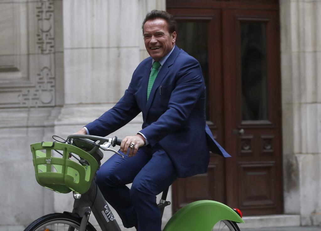 Arnold Schwarzenegger arrives on bicycle to meet Paris mayor Anne HIdalgo, Monday Dec. 11, 2017 in Paris. Schwarzenegger is in Paris to attend the One Planet climate summit Tuesday with more than 50 world leaders and co-hosted by the U.N. and the World Bank. (AP Photo/Thibault Camus)