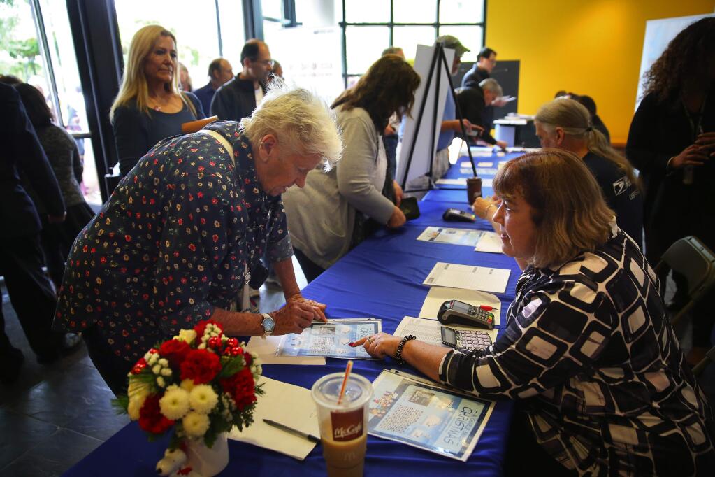 Retired Postal Service letter carrier and Peanuts fan Linda Lee, left, purchases A Charlie Brown Christmas stamps from Fulton Postmaster Maureen Butcher, during the first day of issue at the Charles M. Schulz Musuem, in Santa Rosa, on Thursday, October 1, 2015. (Christopher Chung/ The Press Democrat)