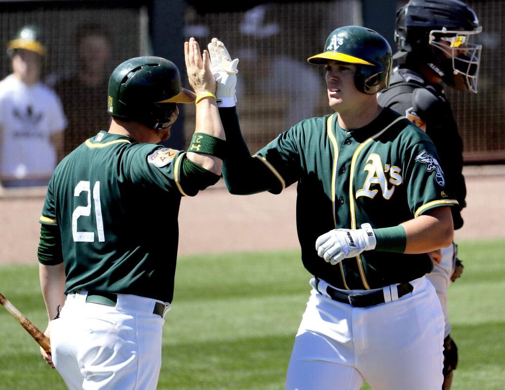Oakland Athletics' Ryon Healy high-fives Stephen Vogt (21) after hitting a two-run home run against the Chicago White Sox during the second inning of a spring training baseball game, Friday, March 24, 2017, in Mesa, Ariz. (AP Photo/Matt York)
