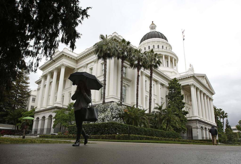 FILE - In this May 16, 2019 file photo a pedestrian walks by the State Capitol, in Sacramento, Calif. California lawmakers will return to work for the second half of their two-year session. Gov. Gavin Newsom must present his budget proposal to lawmakers by Friday, Jan.10, 2020. Lawmakers in the Senate and Assembly have until Jan. 31 to act on bills that were carried over from last year. Democrats have comfortable majorities in both chambers. Democratic leaders say they plan to focus this year on combating homelessness, protecting the environment and mitigating impacts from wildfires. (AP Photo/Rich Pedroncelli,File)