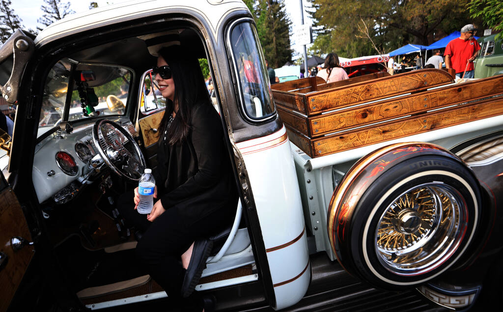 Denisse Ledezma of EWindsor watches the Luther Burbank Center’s Youth Mariachi Group perform from her husband's truck, prior to the unveiling of The Marylou Lowrider Project, a Santa Rosa Police Department patrol car dedicated to Marylou Armer, Saturday, March 26, 2022 in Santa Rosa.   (Kent Porter / The Press Democrat) 2022