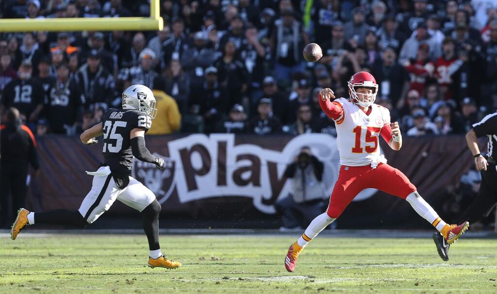 Kansas City Chiefs quarterback Patrick Mahomes throws a pass on the run from Oakland Raiders safety Erik Harris during their game in Oakland on Sunday, December 2, 2018. (Christopher Chung/ The Press Democrat)