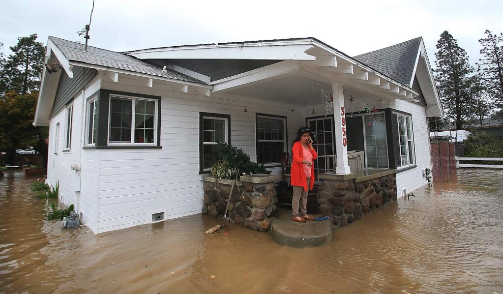 Hermilla Ortega talks to a friend via phone as floodwater from the Petaluma River back up in to her home and property along Petaluma Blvd. North in Petaluma, Sunday Jan. 8, 2017. (Kent Porter / The Press Democrat) 2017