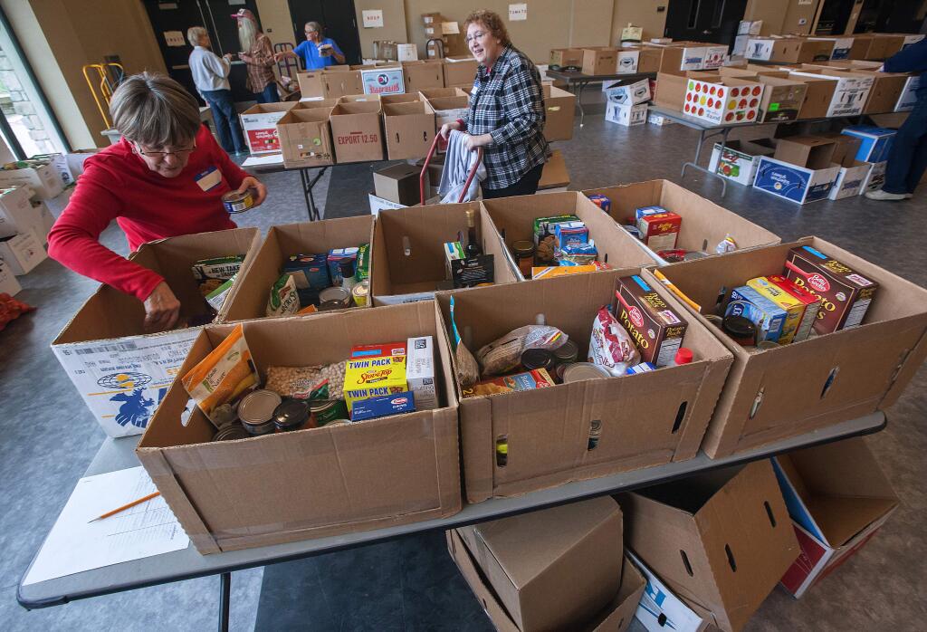 Robbi Pengelly/Index-TribuneAt the Hanna Boys Center, FISH volunteers Susei Petersen, left, and Mikayla DeRosier fill food 'baskets' for distrilbution on Saturday. Some 400 boxes of food are expected to be given out to those in need.