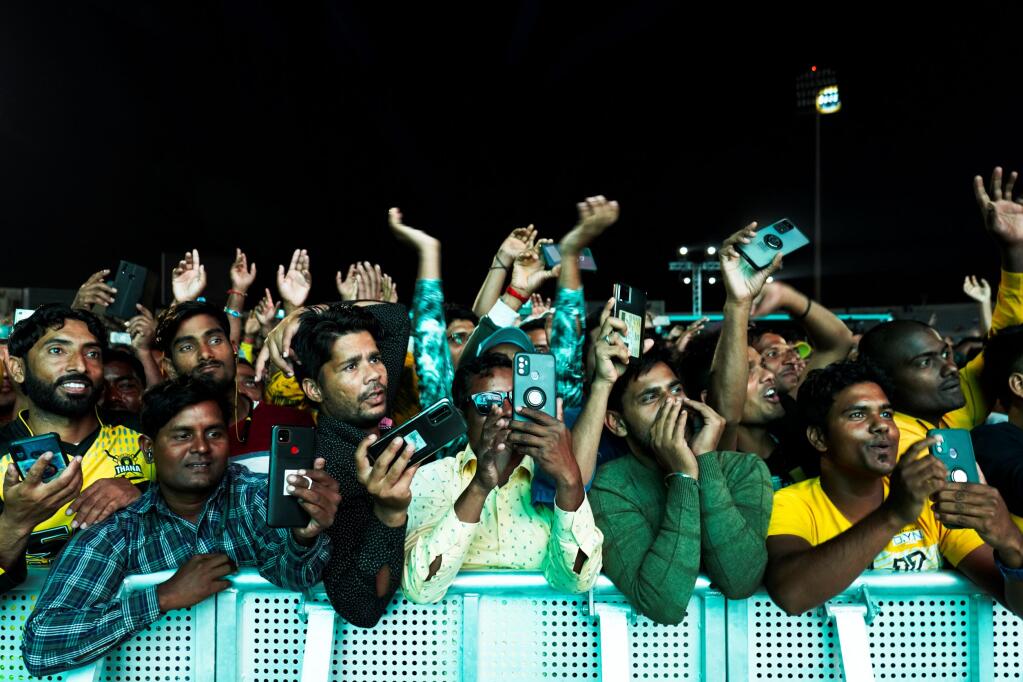 Laborers cheer at a fan festival at the Asian Town cricket stadium in Doha, Qatar, Friday, Nov. 25, 2022. Far from the luxury hotels and sprawling new stadiums emblematic of Doha during the World Cup, scores of soccer-mad South Asian workers poured into a converted cricket stadium in the city's desert outskirts to enjoy the tournament they helped create. (AP Photo/Jon Gambrell)