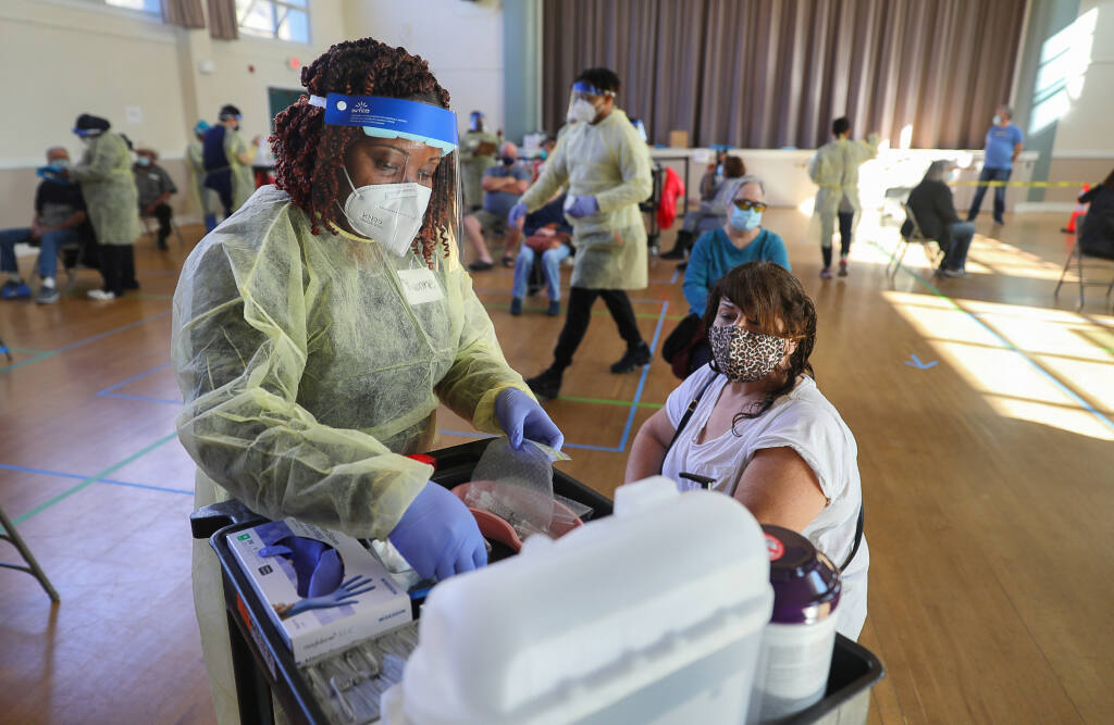 Registered nurse Yvonne Emmanuel prepares to administer the Pfizer COVID-19 vaccine to Nicole Jenkins at the Sonoma Valley Veterans Memorial Hall on Tuesday, Feb. 16, 2021.  (Christopher Chung/ The Press Democrat)