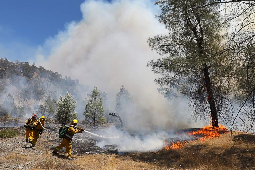 Manteca Fire Department firefighters put water on a hotspot near Cache Creek Road, in the Pawnee Fire east of Clearlake Oaks on Monday, June 25, 2018. (Christopher Chung/ The Press Democrat)
