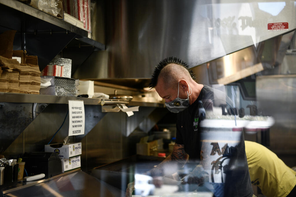 A kitchen staffer works behind the counter of a restaurant in Los Angeles on June 8, 2021. (Photo by Pablo Unzueta for CalMatters)