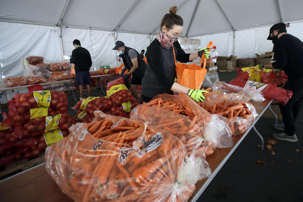 In this April 18, 2020, file photo, San Francisco-Marin Food Bank volunteers pack food into bags to be delivered to people in San Francisco. Food banks and anti-hunger advocates are bracing for the end of a pandemic-era boost in food assistance that the federal government has been providing for nearly three years. Photo by Jeff Chiu, AP Photo