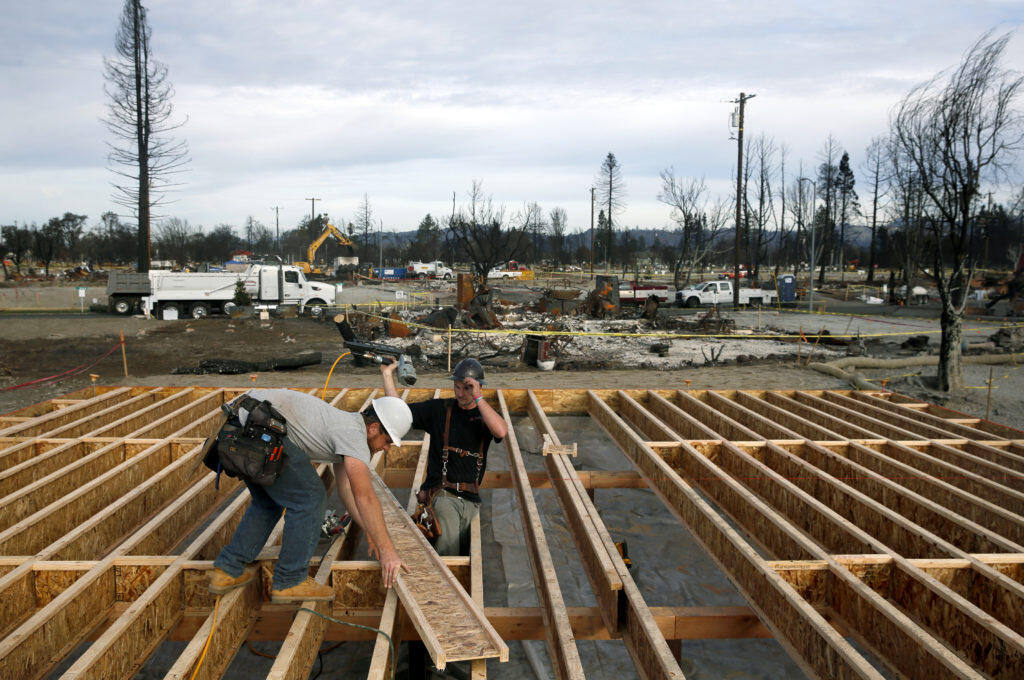 Jesse Merritt, left, and Joey Horst with Lake County Contractors install floor joists as they rebuild a home on Kerry Lane in Coffey Park in Santa Rosa, on Tuesday, January 2, 2018. (BETH SCHLANKER/ The Press Democrat)