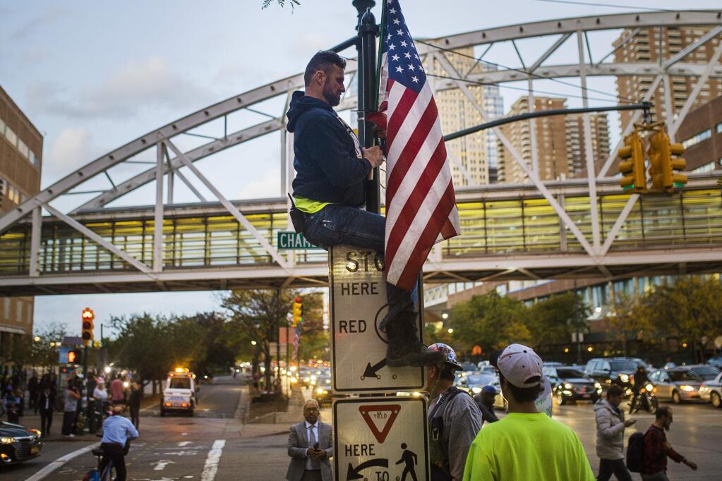 A man places a U.S. flag in memory of the victims of the truck attack in New York this week. (ANDRES KURDACKI / Associated Press)