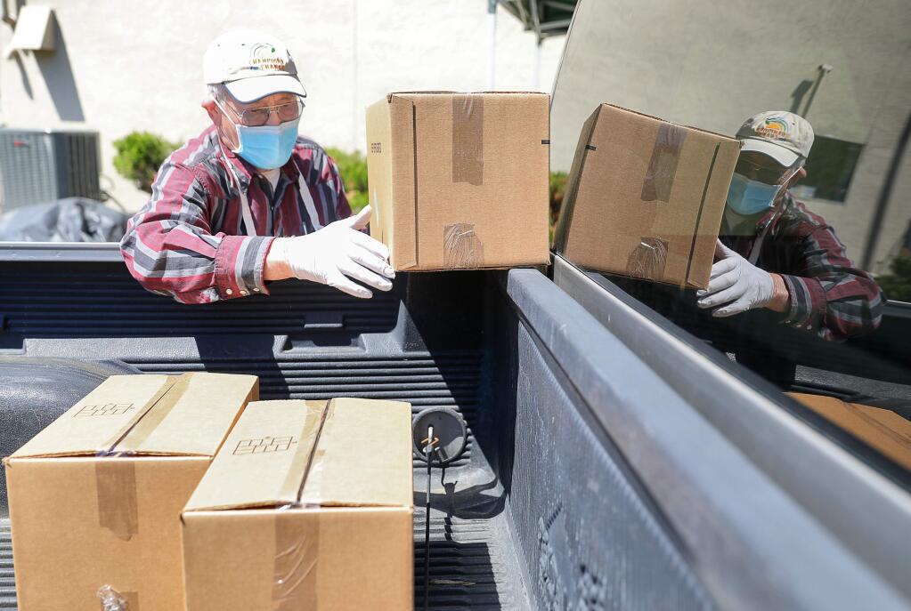 Redwood Empire Food Bank volunteer Al Lenhardt loads boxes of food into a client's truck during a food distribution event at Shiloh Neighborhood Church, in Santa Rosa on Wednesday, April 15, 2020. (Christopher Chung/ The Press Democrat)