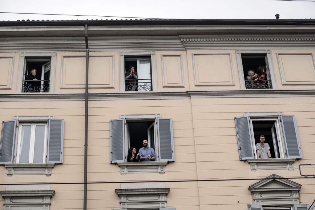 People applaud doctors and nurses from their windows in Milan, March 14, 2020. Italians remain essentially under house arrest as the nation, the European front in the global fight against the coronavirus, has ordered extraordinary restrictions on their movement to prevent contagions. (Alessandro Grassani/The New York Times)