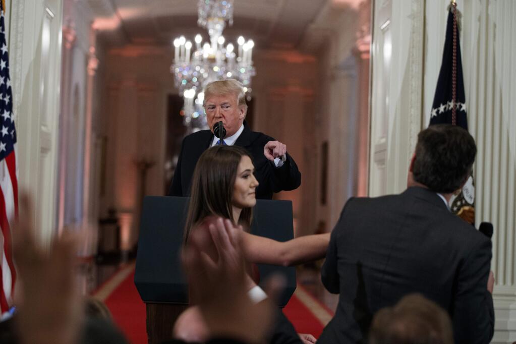 FILE - In this Nov. 7, 2018 file photo, President Donald Trump watches as a White House aide reaches to take away a microphone from CNN journalist Jim Acosta during a news conference in the East Room of the White House in Washington. CNN is suing the Trump administration, demanding that Acosta's press credentials to cover the White House be returned. The administration revoked them last week following President Trump's contentious news conference, where Acosta refused to give up a microphone when the president said he didn't want to hear anything more from him. (AP Photo/Evan Vucci, File)