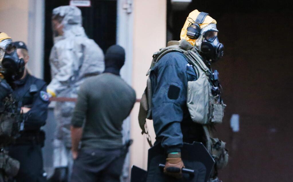 In this Tuesday June 12, 2018 photo, German police officers in protective gear leave an apartment building during an operation in Cologne, Germany. German police are searching the apartment of a 29-year-old Tunisian man who is accused of keeping toxic substances in his home. (David Young/dpa via AP)