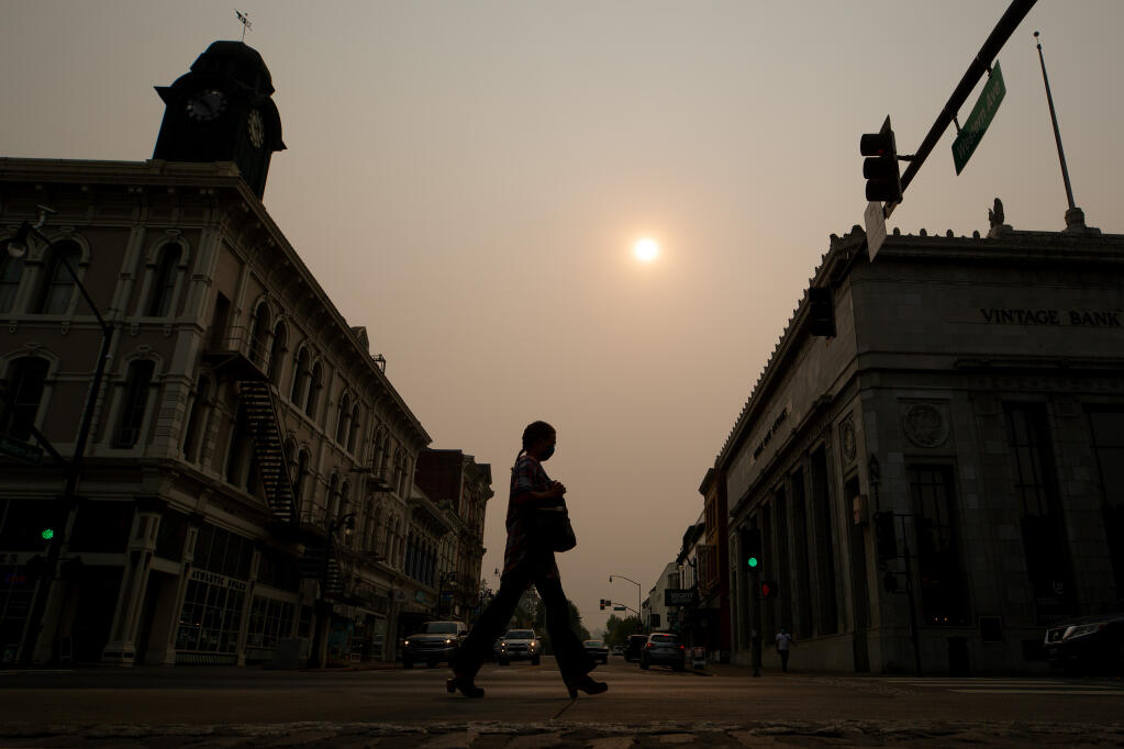 A woman wearing a mask walks along Petaluma Boulevard at Western Avenue on the 25th consecutive Spare the Air day cause by smoke from wildfires across the state in Petaluma on Friday, Sept. 11, 2020. (Alvin A.H. Jornada / The Press Democrat)
