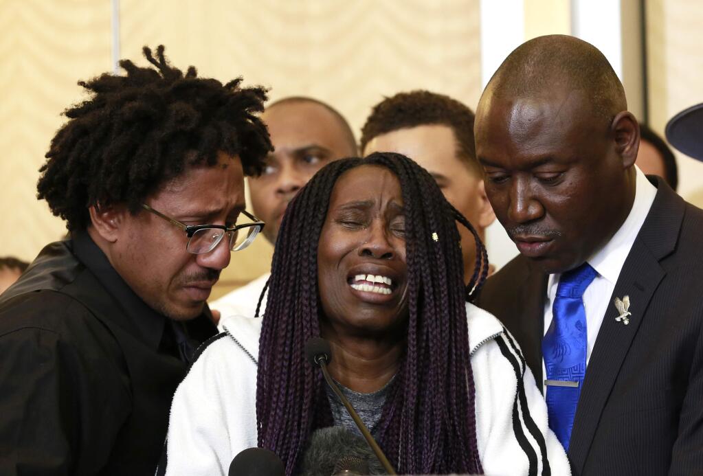 A tearful Sequita Thompson, center, discusses the shooting of her grandson, Stephon Clark, during a news conference, Monday, March 26, 2018, in Sacramento, Calif. Clark, who was unarmed, was shot and killed by Sacramento police officers who were responding to a call about person smashing car windows a week ago. Thompson was accompanied by Clark's brother Ste'vonte Clark, left, and attorney Ben Crump, right. (AP Photo/Rich Pedroncelli)