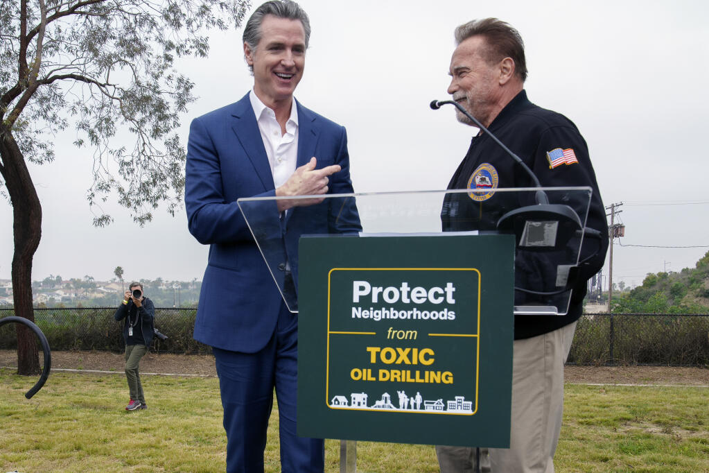 California Gov. Gavin Newsom, left, joins former California Gov. Arnold Schwarzenegger during a news conference for the Campaign for a Safe and Healthy California campaign for Keep The Law (SB 1137) in Inglewood, Calif., on Friday, March. 22, 2024. The law, if upheld, would require all oil or gas production facilities or wells within a health protection zone to comply with new regulations. (AP Photo/Damian Dovarganes)