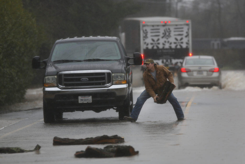 Doug Hall clears logs away that had washed onto Broadway in the Schellville area south of Sonoma, California  on Tuesday, February 26, 2019 . (BETH SCHLANKER/The Press Democrat)