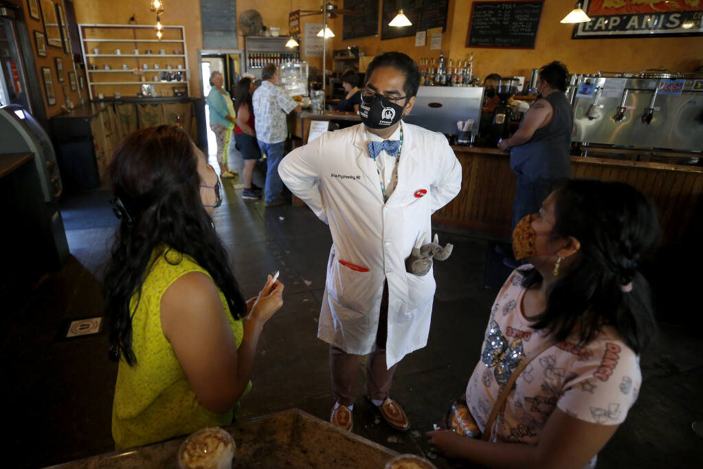 Dr. Brian Prystowsky talks with Irma Garcia and her daughter Francis Escobedo, 9, at A'Roma Roasters Coffee & Tea as he tries to spread the word about free Covid-19 vaccines available Sunday at the Arlene Francis Center in Santa Rosa, Calif., on Sunday, June 27, 2021.(Beth Schlanker/The Press Democrat)