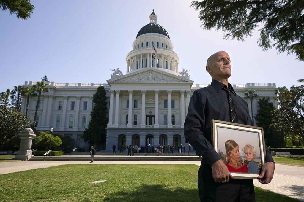 Doug Forbes poses for a portrait in front of the Capitol while holding a picture of his daughter Roxie, who drowned at a day camp in Pasadena a few years ago and his wife Elena Matyas, who passed away recently. Photo by Fred Greaves for CalMatters
