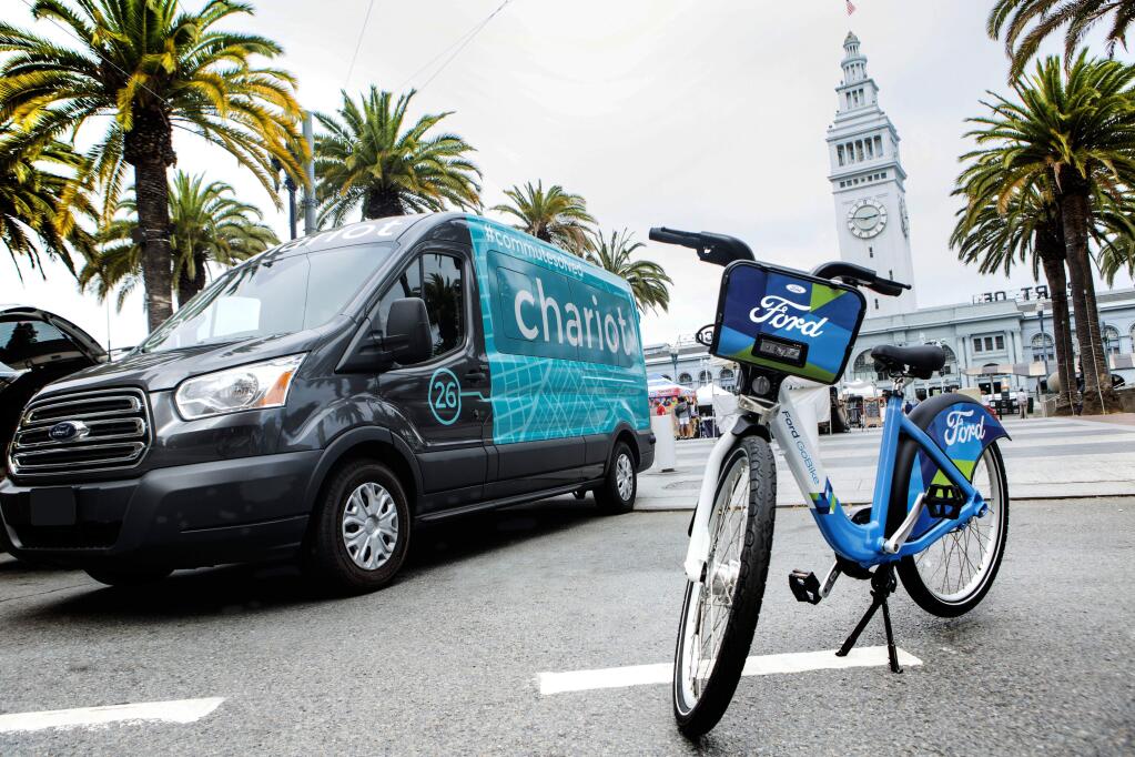 This Thursday, Sept. 8, 2016, photo taken in San Francisco and provided by Ford Motor Company shows a Ford Transit passenger van operated by Chariot shuttle service and a bicycle operated by bike-share company Motivate. Ford Motor Co. announced Friday, Sept. 9, 2016, it is buying the app-based shuttle service Chariot and is partnering with bike-share company Motivate as part of its ongoing effort to expand its traditional business. (Tommy Lau/Ford Motor Co. via AP)