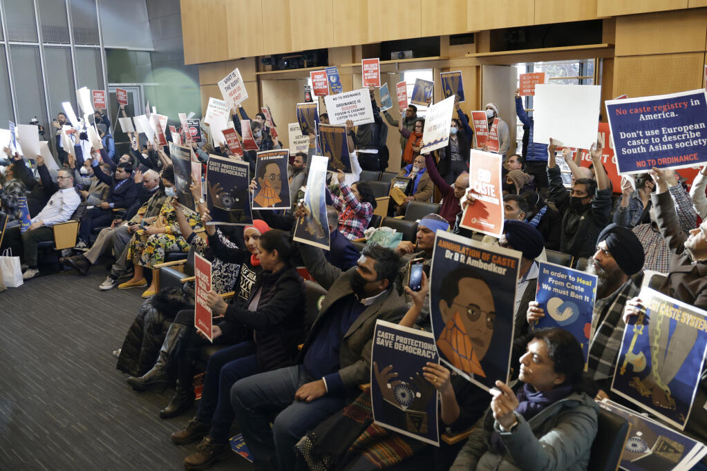 People react during a crowded public hearing in the Seattle City Council chambers regarding an ordinance to add caste to Seattle's anti-discrimination laws, Tuesday, Feb. 21, 2023, in Seattle. Council Member Kshama Sawant proposed the ordinance. (AP Photo/John Froschauer)