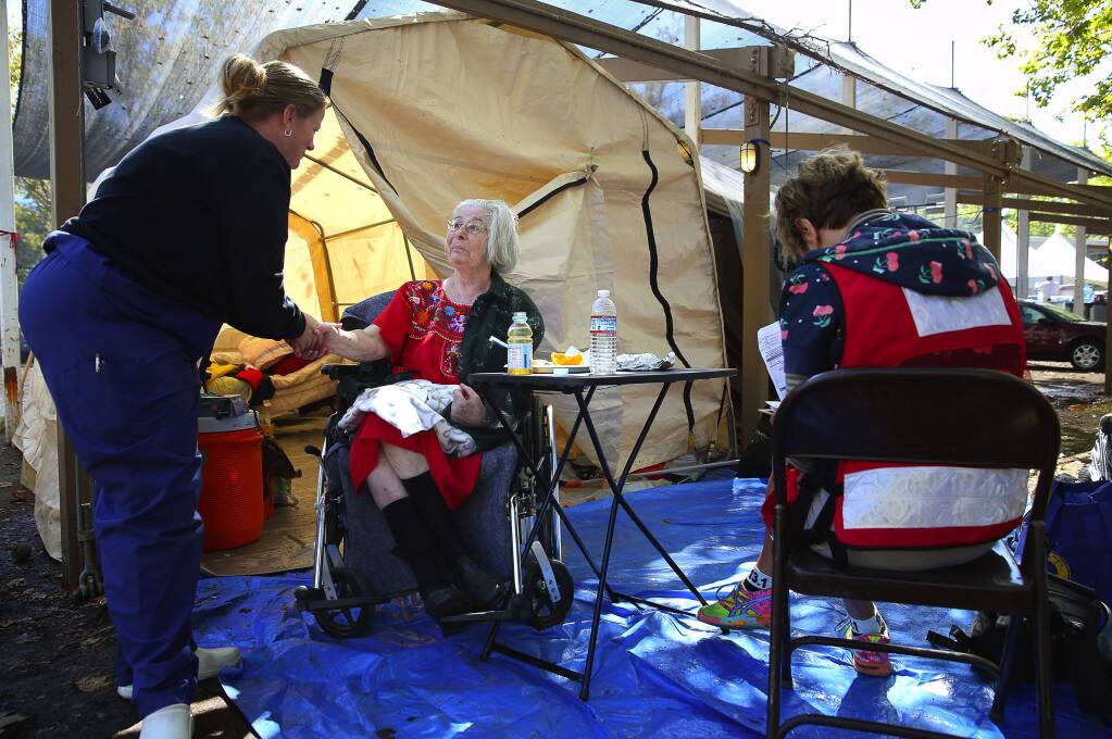 Wendi Thomas, a registered nurse at Petaluma Valley Hospital, talks with Middletown evacuee Merna Scott, 72, while Red Cross disaster relief worker Elsa Von Schopp helps with paperwork at the Valley fire evacuation center, at the Napa County Fairgrounds, in Calistoga, on Thursday, September 17, 2015. (Christopher Chung/ The Press Democrat)
