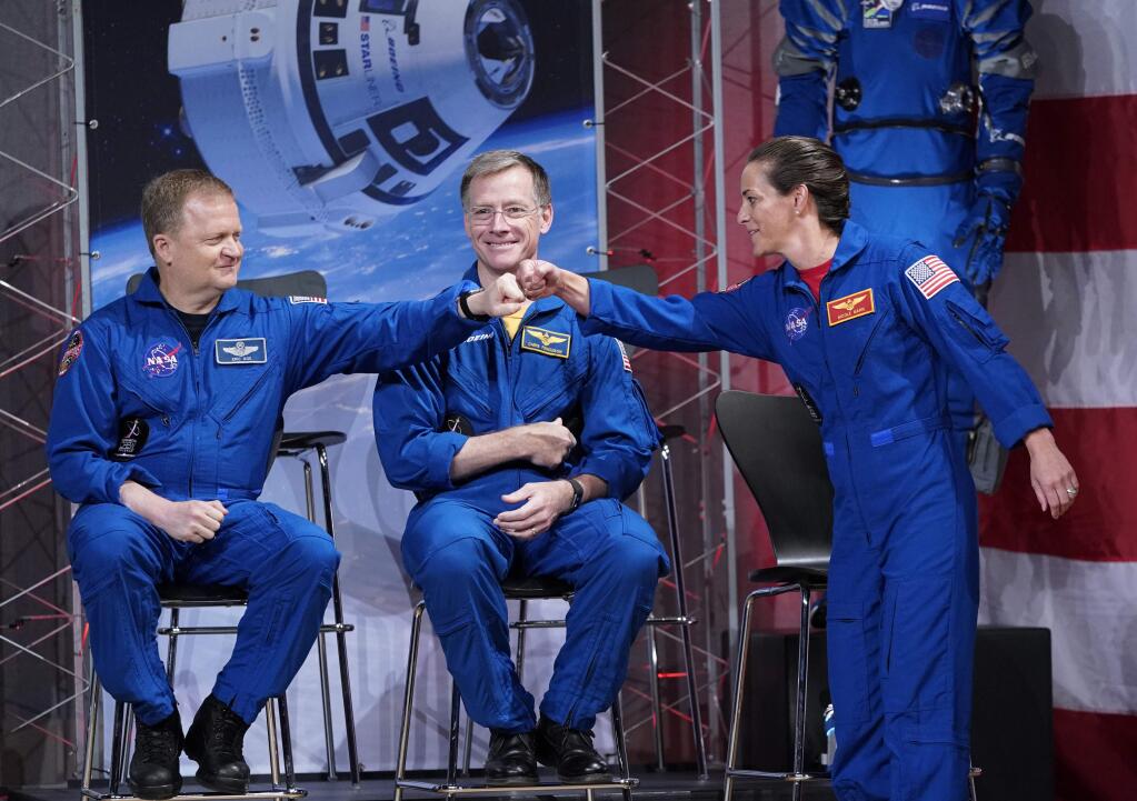 Astronauts Nicole Mann and Eric Boe bump fists in front of Christopher Ferguson after being introduced Friday during a NASA event to announce the astronauts assigned to crew the first flight tests and missions of the Boeing CST-100 Starliner and SpaceX Crew Dragon, The astronauts will ride the first commercial capsules into orbit next year and return human launches to the U.S. (DAVID J. PHILLIP / Associated Press)