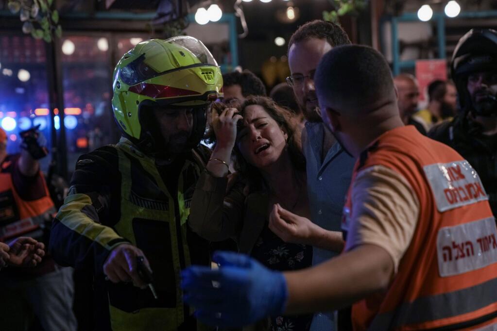 A woman reacts at the scene of a shooting attack In Tel Aviv, Israel, Thursday, April 7, 2022. Israeli health officials say two people were killed and at least eight others wounded in a shooting in central Tel Aviv. The shooting on Thursday evening, the fourth attack in recent weeks, occurred in a crowded area with several bars and restaurants. (AP Photo/Ariel Schalit).