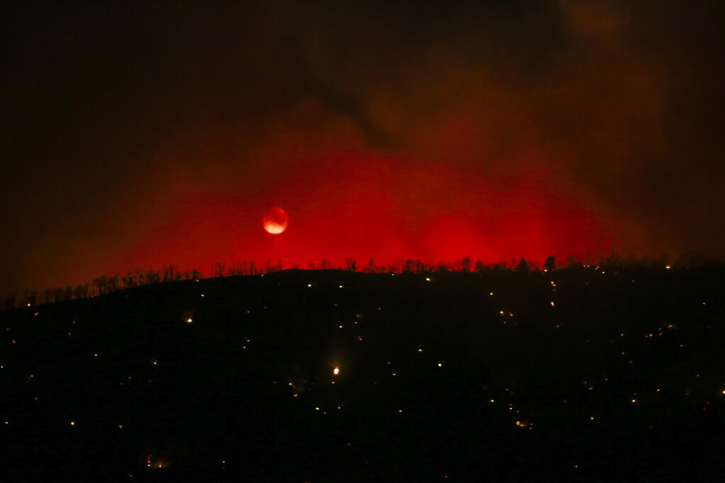 The moon is seen as the Sheep fire burns in Wrightwood, Calif., Monday, June 13, 2022. (AP Photo/Ringo H.W. Chiu)