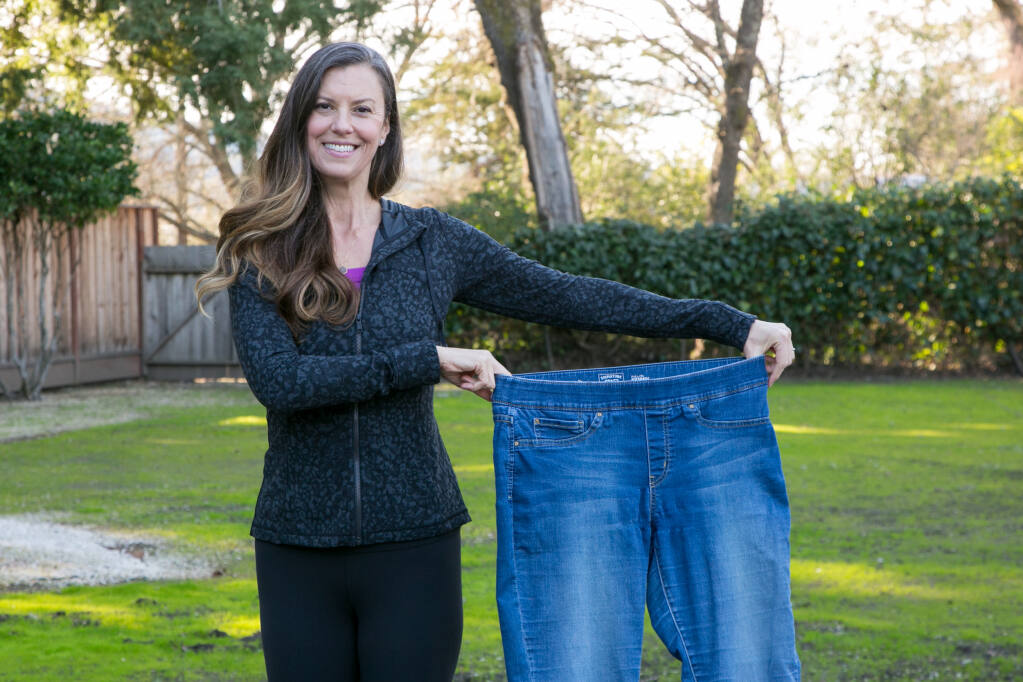 Adrienne Shubin, who lost 70 pounds during the pandemic, holds a pair of her old jeans at her house in Kenwood, Wednesday, Feb. 17, 2021. (Photo by Julie Vader/Special to the Index-Tribune.)