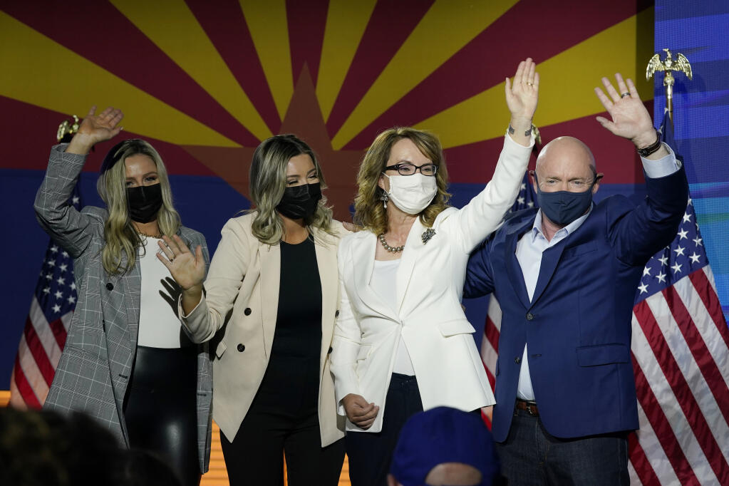 Mark Kelly, right, Arizona Democratic candidate for U.S. Senate, waves to supporters along with his wife Gabrielle Giffords, second from right, and daughters, Claire Kelly, left, and Claudia Kelly, second from left, during an election night event Tuesday, Nov. 3, 2020 in Tucson, Ariz. (AP Photo/Ross D. Franklin)