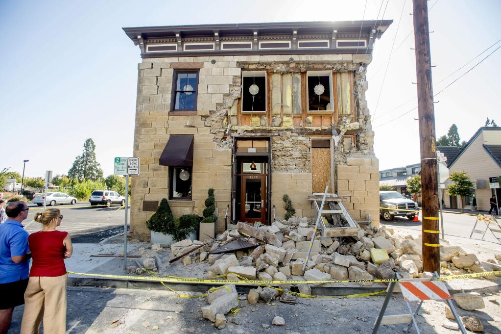 In this Aug. 24, 2014 file photo pedestrians examine a crumbling facade following an earthquake at the Vintner's Collective tasting room in Napa. (AP Photo/Noah Berger, File)