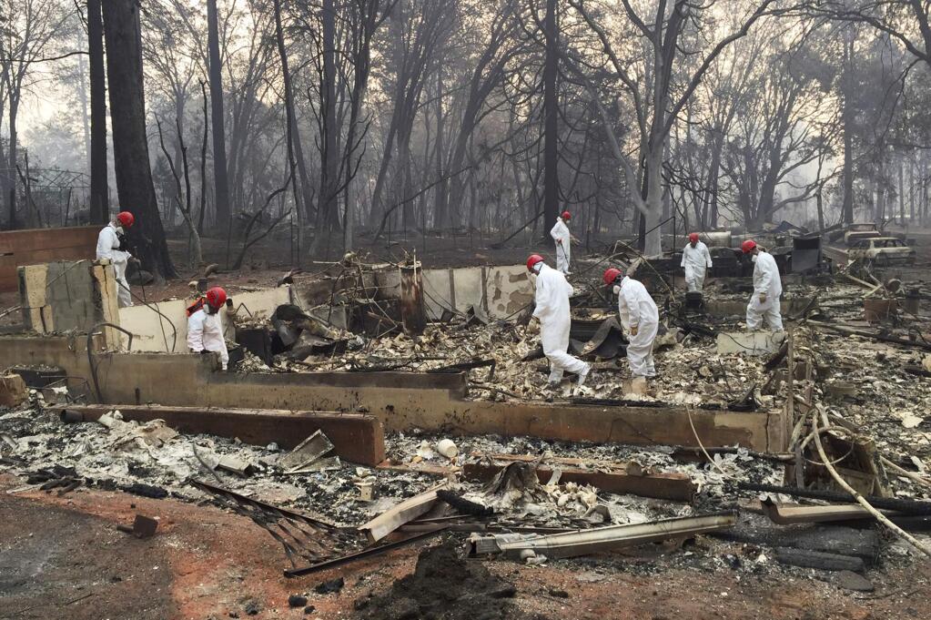 FILE - In this Nov. 15, 2018 file photo, volunteer rescue workers search for human remains in the rubble of homes burned in the Camp fire in Paradise, Calif. (AP Photo/Terry Chea, File)