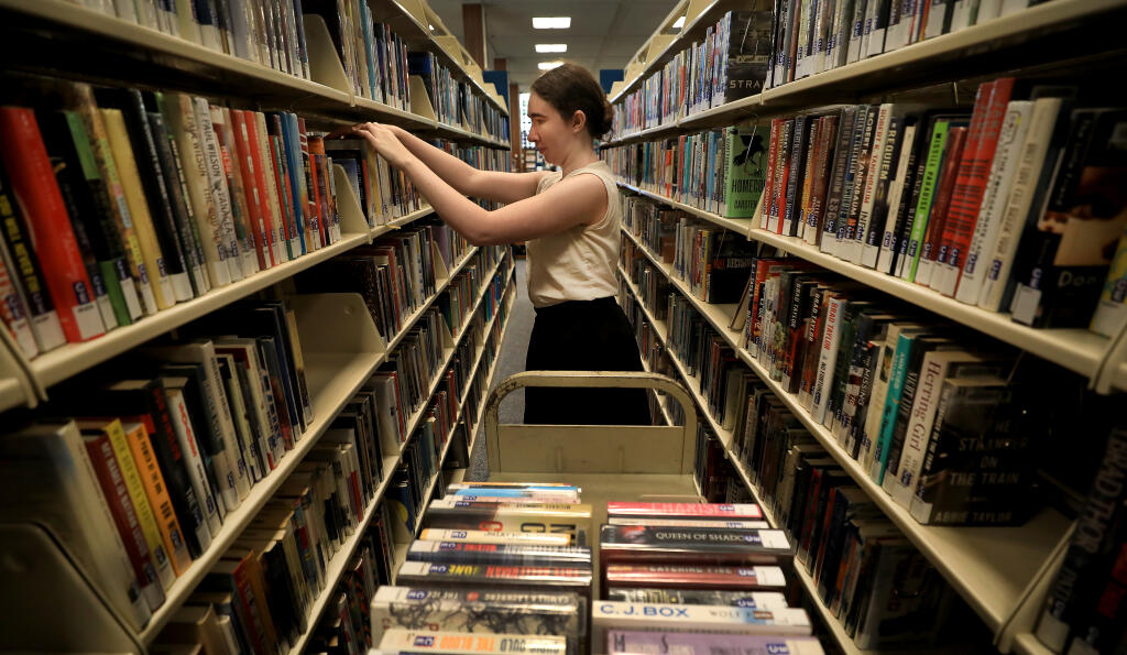 Logan Manchester refiles returned books at the main branch of the Sonoma County Library, Tuesday, June 25, 2019 in Santa Rosa. (Kent Porter / The Press Democrat)
