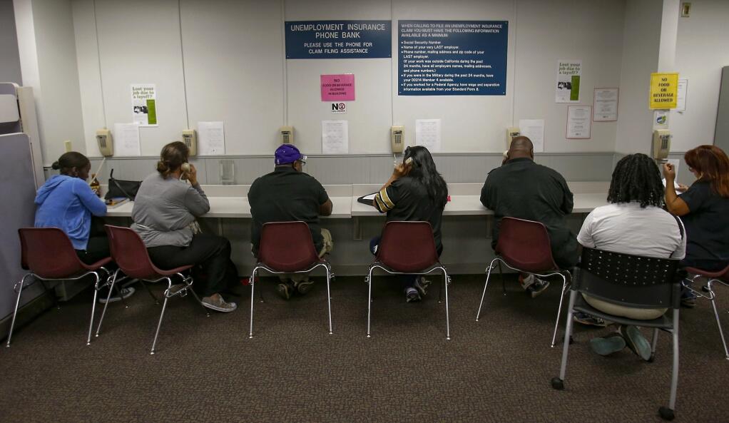 FILE - In this Sept. 20, 2013, file photo, visitors use the Unemployment Insurance phone bank at the California Employment Development Department, EDD office in Sacramento, Calif. (AP Photo/Rich Pedroncelli, File)