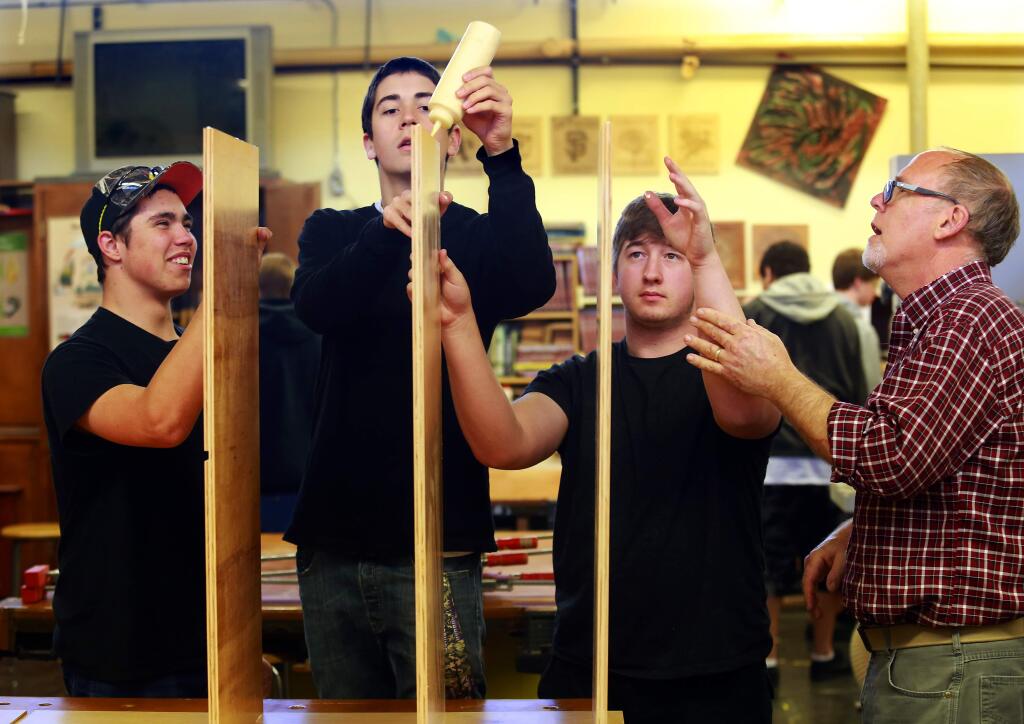 (R to L) Rancho Cotate woodshop teacher Bill Hartman, right, with Tyler Van Guilder, Jonny Hunter and Patrick Urteago apply glue to shelves on one of the 60 armoires the class is building for Social Advocates for Youth's new Dream Center. (JOHN BURGESS / The Press Democrat)