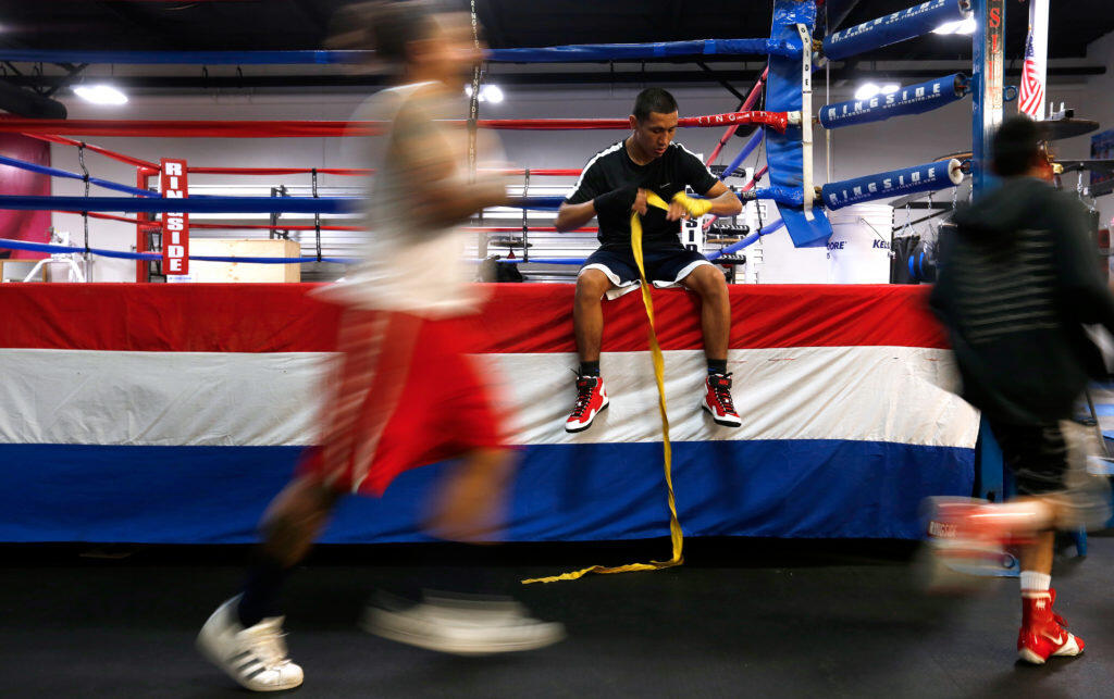Jonathan Rubio, 18, wraps his hands before a workout while other boxing club members run laps around the ring at Double Punches Boxing Club in Santa Rosa, California, on Tuesday, August 28, 2018. (Alvin Jornada / The Press Democrat)