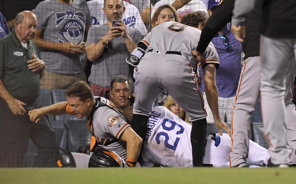 San Francisco Giants catcher Nick Hundley, left, and first base coach George Lombard, right, fall to the ground while Hunter Pence stands over them after Hundley and Yasiel Puig scuffled during the seventh inning of a baseball game, Tuesday, Aug. 14, 2018, in Los Angeles. (AP Photo/Mark J. Terrill)