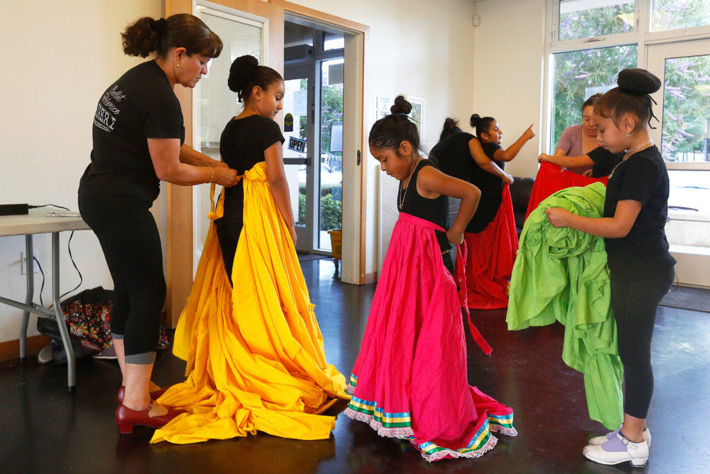 Ballet Folklorico Ireri director Maria Serrano, left, helps her younger dancers with their skirts during dance practice, in Petaluma, California, on Thursday, August 16, 2018. (Alvin Jornada / The Press Democrat)