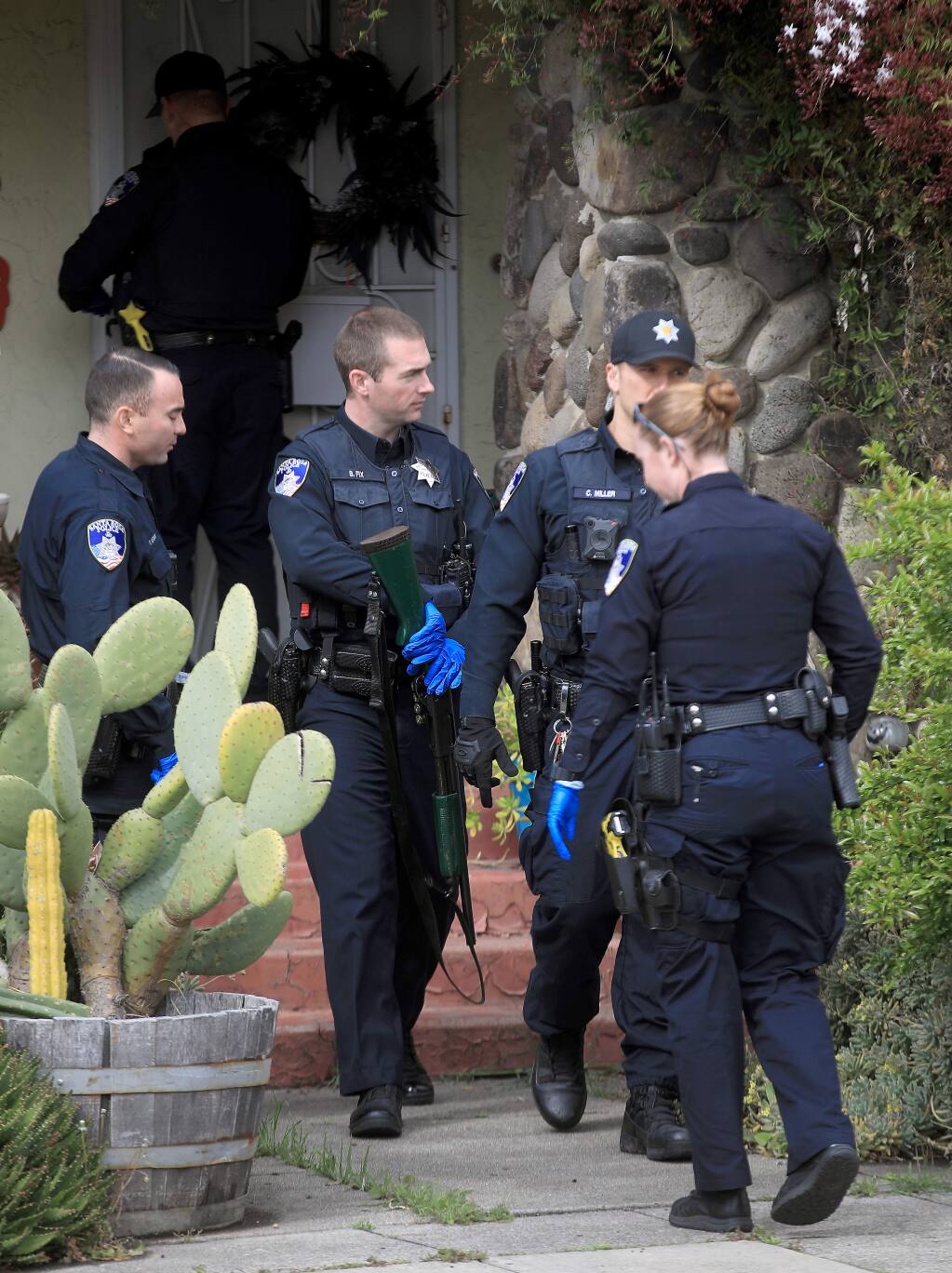 Gloved up to take precautions, Santa Rosa police officers gather after searching a home in Santa Rosa, Tuesday, March 24, 2020. Three officers with the SRPD have tested positive for COVID-19.(Kent Porter / The Press Democrat) 2020