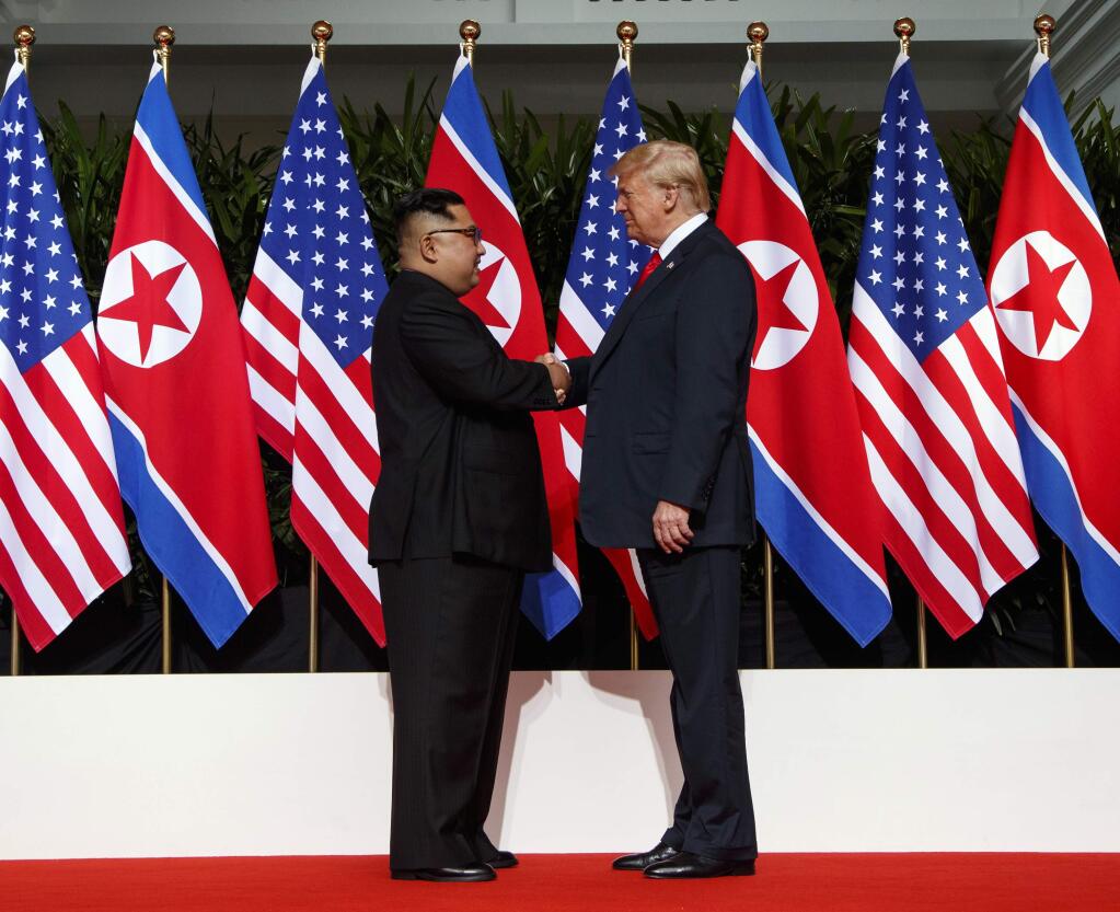 North Korean leader Kim Jong Un, left, and U.S. President Donald Trump shake hands prior to their meeting on Sentosa Island in Singapore Tuesday, June 12, 2018. Kim is about 170 centimeters (5.8 feet) tall, about 20 centimeters (7.2 inches) shorter than Trump, according to media reports. But when the two stood together during Tuesday's meeting, the difference in their heights wasn't that noticeable. (AP Photo/Evan Vucci)
