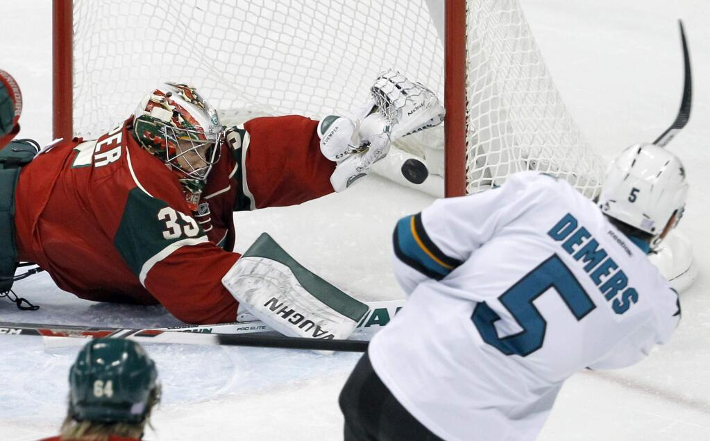 Minnesota Wild goalie Darcy Kuemper, top left, cannot get to a shot by San Jose Sharks defenseman Jason Demers (5), but it is ruled no goal due to accidental interference during the first period of an NHL game in St. Paul, Minn., Thursday, Oct. 30, 2014. (AP Photo/Ann Heisenfelt)