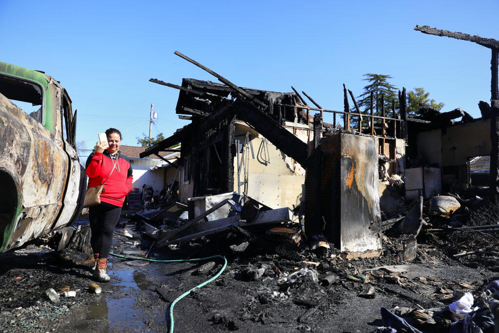 Gabriela Marquez walks among the burned remains of the home that she was living in with her family, along West College Avenue, in Santa Rosa, on Wednesday, March 28, 2018.   (Christopher Chung/ The Press Democrat)