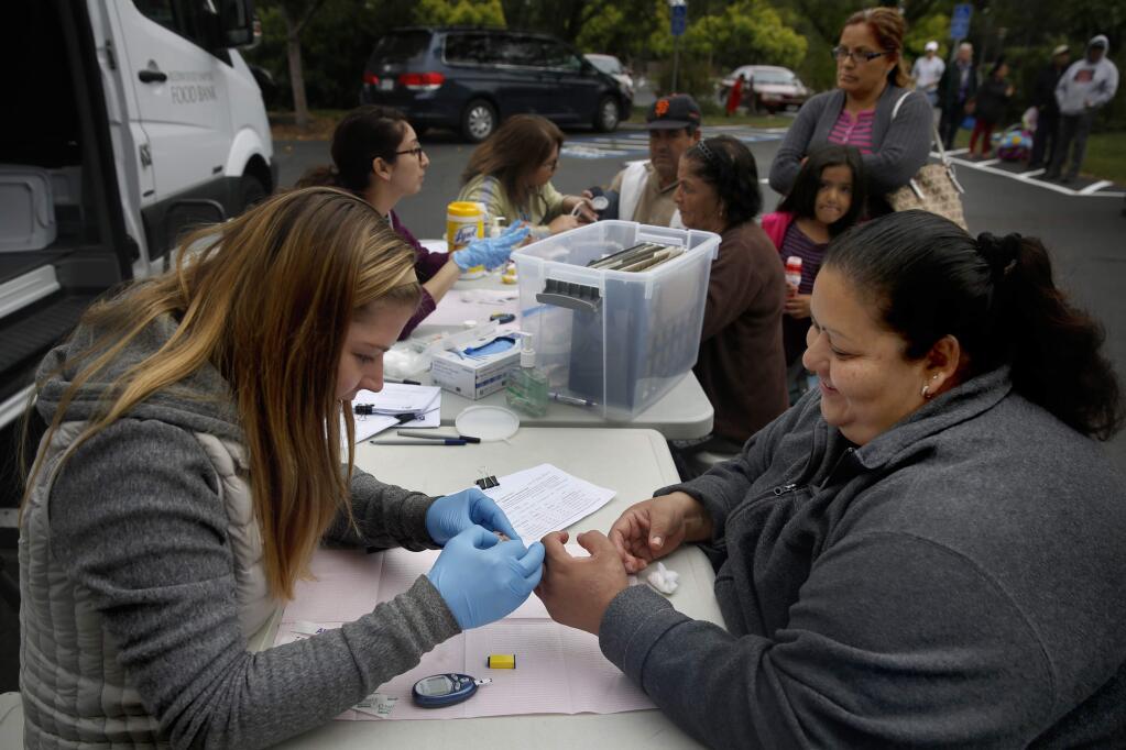 PHOTO: 2 by BETH SCHLANKER / The Press Democrat -GETTING SCREENED: Alida Peterson, left, a registered dietician with the Diabetes Wellness Project, collects a blood sample from Claudia Tapia at St. Leo's Catholic Church in Agua Caliente.