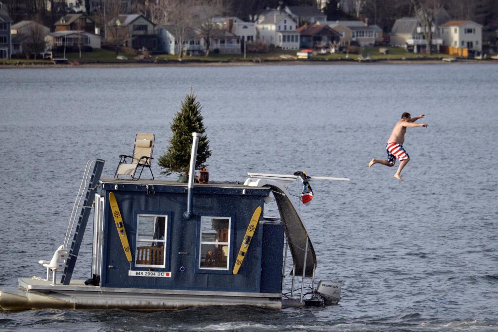 FILE - In this Dec. 24, 2015 file photo, a man jumps into Pontoosuc Lake in Pittsfield, Mass. The New England lake is typically frozen in December, but unusually warm temperatures have kept the water open. On Thursday, Oct. 18, 2018, the National Weather Service forecasted a warmer than normal 2018-2019 winter for the northern and western three-quarters of the U.S. (Ben Garver/The Berkshire Eagle via AP)